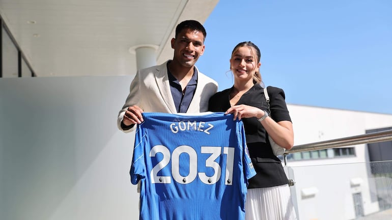Diego Gómez y una mujer sonríen sosteniendo camiseta azul con 'GOMEZ 2031 N' en un día soleado.