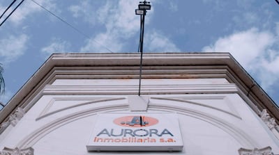 Edificio de AURORA Inmobiliaria S.A. con letrero visible, bajo un cielo parcialmente nublado.