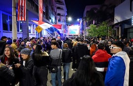 Hinchas de la selección paraguaya, con ropa oscura y banderas tricolores, se concentran frente a una pantalla en la calle Palma.