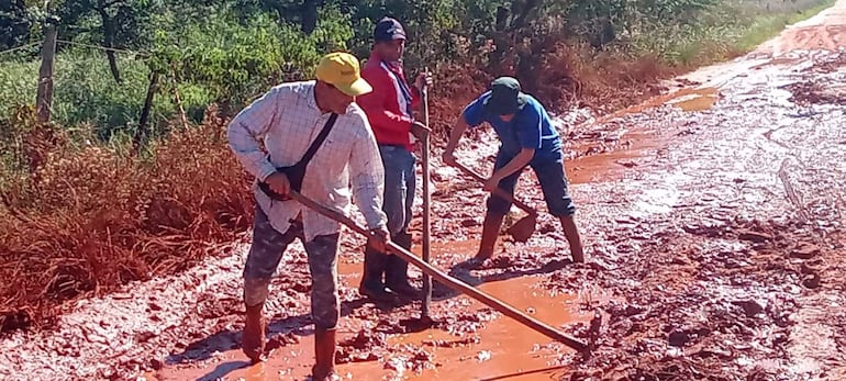 Vecinos de la compañía Aguai’y, con azadas en mano, intentan improvisar la canalización del camino rural.