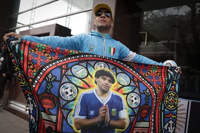Un aficionado muestra una bandera con la imagen de la leyenda del fútbol argentino Diego Maradona frente al tribunal, antes de una audiencia del juicio por la muerte de Maradona en San Isidro, provincia de Buenos Aires, Argentina, el 8 de octubre de 2026. (Foto de AFP)