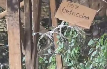 Cartulina con advertencia ‘Tiene electricidad’ junto a cables en un entorno de madera expuesta y restos de estructura.