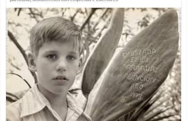 Niño de 10 años con camisa clara y expresión seria, junto a planta etiquetada 'EMBAJADA DE EE.UU. PARAGUAY ASUNCIÓN AÑO 1973'.