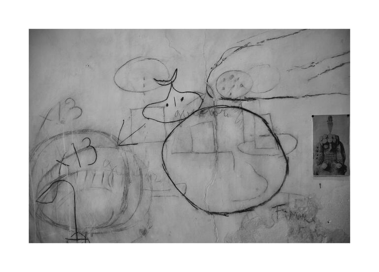 Pared con dibujos abstractos en un ambiente de abandono, sin figuras humanas presentes.
