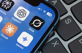Teléfono móvil con pantalla activa, mostrando aplicaciones de inteligencia artificial sobre un teclado en un ambiente informal.