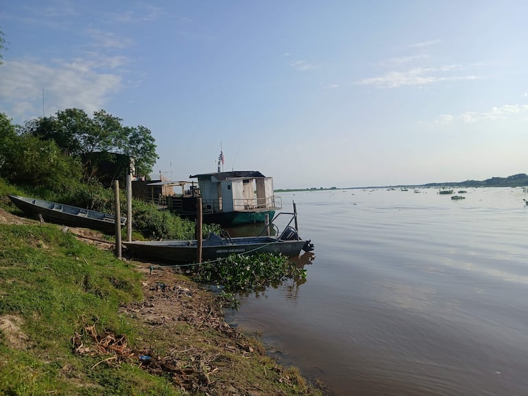 Canoas de madera amarradas en la orilla del río, rodeadas de vegetación y cielo despejado en Fuerte Olimpo.