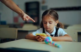 Una niña revisa un teléfono celular en el aula.