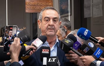 Yamil Esgaib en el centro, sosteniendo micrófonos y hablando, con múltiples cámaras enfocándolo en un entorno burocrático.