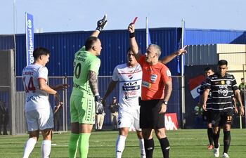 El árbitro Carlos Paul Benítez muestra la tarjeta roja a Santiago Rojas, portero de Nacional, en un partido frente a Olimpia por la fecha 21 del torneo Apertura 2025 del ´futbol paraguayo en el estadio Arsenio Erico, Asunción, Paraguay.