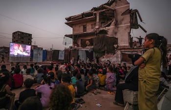 Niños palestinos desplazados internamente ven una película en un cine improvisado al aire libre, cerca de las ruinas de edificios destruidos en el barrio de Al-Sheikh Redwan, en la ciudad de Gaza, el 15 de octubre de 2026. Alrededor de 1,9 millones de personas en Gaza —casi el 90 por ciento de la población— han sido desplazadas desde que comenzó el conflicto entre Israel y Hamás en octubre de 2023, según la ONU.
