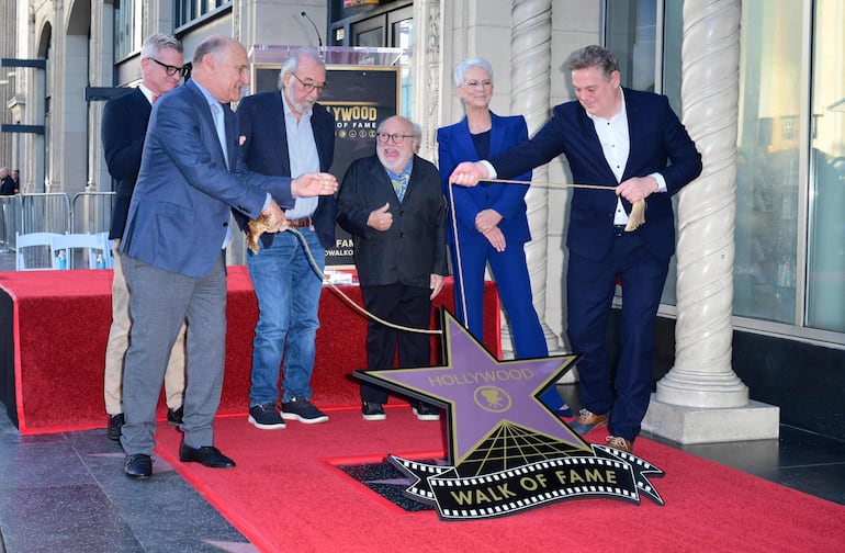 El director, escritor y productor mira emocionado cuando se revela su estrella durante una ceremonia en el Paseo de la Fama de Hollywood, flanqueado por el actor estadounidense Danny DeVito y la actriz estadounidense Jamie Lee Curtis. (Frederic J. BROWN / AFP)