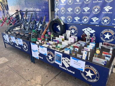 Mesa con productos confiscados, incluyendo armas y medicamentos, mientras un agente aduanero observa la escena.