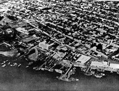 Vista aérea de un puerto con embarcaciones amarradas y edificios de estilo colonial y moderno en Asunción, en blanco y negro.