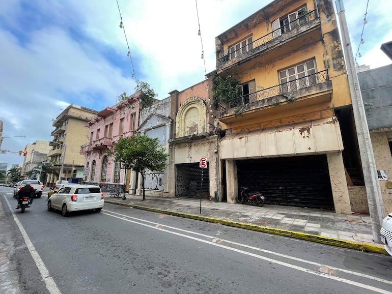 Calles vacías en Asunción con edificios antiguos, uno rosa y otro amarillo, deteriorados y con grafiti.