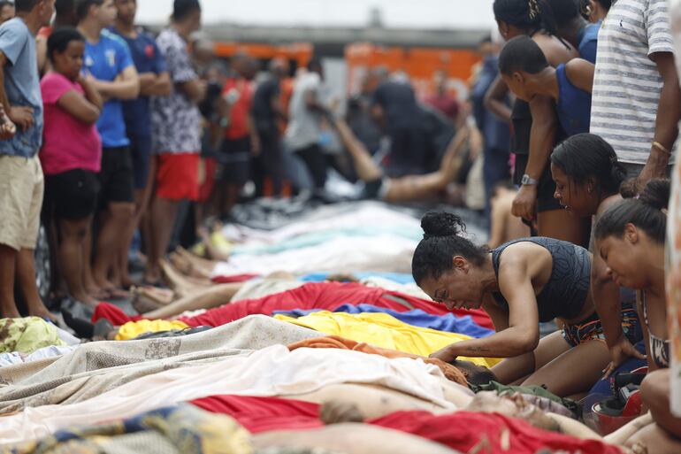 CONTENIDO GRÁFICO EXPLICITO. Una mujer llora frente a cuerpos sin vida en una calle este miércoles, en Río de Janeiro (Brasil). La operación policial lanzada el martes en Río de Janeiro, la más letal de la historia de la ciudad brasileña, dejó 132 muertos, entre ellos cuatro agentes.