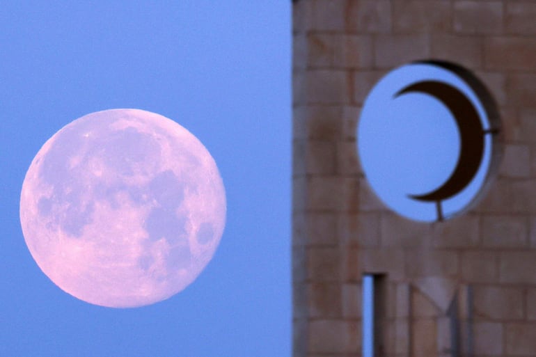 Una luna llena, también conocida como la “luna de sangre”, se eleva detrás del minarete de una mezquita en la ciudad de Ramala, en la Cisjordania ocupada, el 4 de marzo de 2026.