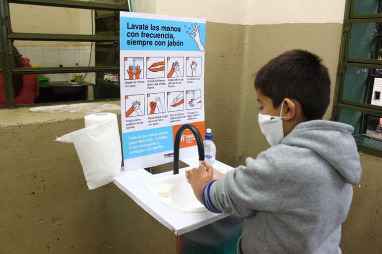 Un niño con síntomas gripales se lava las manos antes de ingresar a clases. 