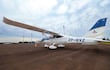 Un avión ligero blanco y azul con matrícula ZP-BVZ, sin personas visibles, en un aeropuerto con pista de tierra y conos naranjas.