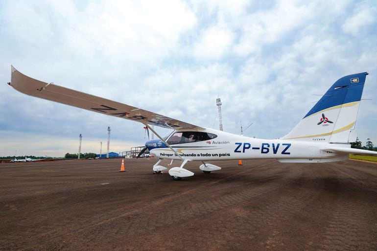 Un avión ligero blanco y azul con matrícula ZP-BVZ, sin personas visibles, en un aeropuerto con pista de tierra y conos naranjas.