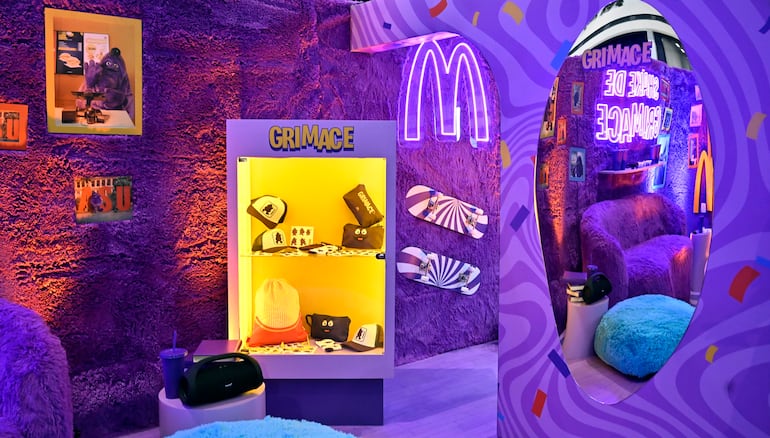 Espacio decorado en púrpura con mueble exhibidor de productos de Grimace y espejo festivo.