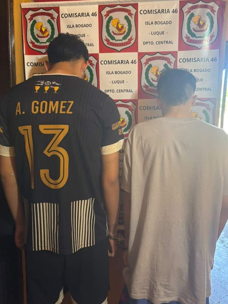 Adolescentes de espaldas en la comisaría 46, uno con camiseta negra y el nombre 'A. GOMEZ', el otro con camiseta blanca.