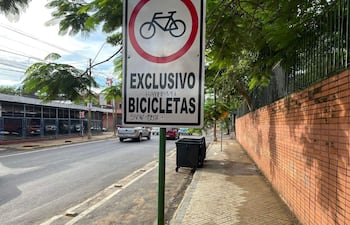 Cartel de 'EXCLUSIVO BICICLETAS' en bicisenda de Mariscal López, rodeado de vehículos y vegetación.