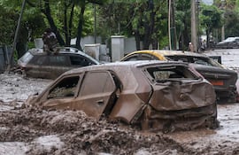 Una persona espera sobre un vehículo afectado por un aluvión este jueves, en la comuna de Las Condes, en Santiago (Chile).