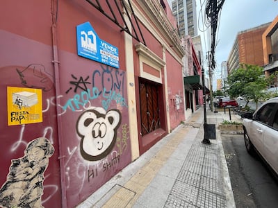 Calle vacía adornada con grafitis artísticos, incluyendo un rostro de oso y una niña abrazando un gato.