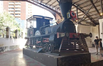 Visitores, incluidos dos adultos y un niño, observan locomotora de vapor negra con detalles rojos en el museo ferroviario.