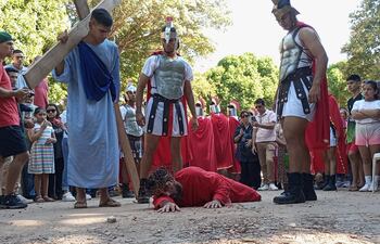Simón de Cirene sostiene la pesada cruz de Jesús, que agoniza en el suelo de tanto dolor.