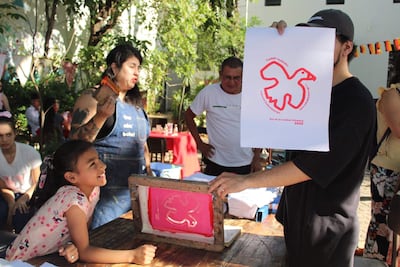 Niña sonriente junto a adulta en camiseta de denim, todos en un ambiente festivo con comida y decoración colorida.