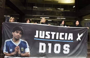 Personas sostienen un cartel con la imagen de Diego Armando Maradona este martes, durante el juicio por la muerte del legendario futbolista argentino Maradona, en Buenos Aires (Argentina). EFE