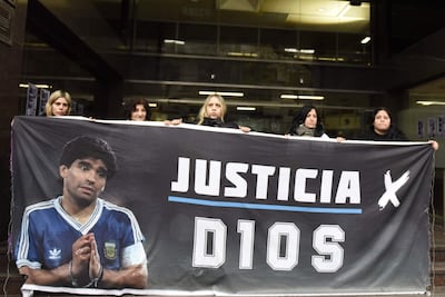 Personas sostienen un cartel con la imagen de Diego Armando Maradona este martes, durante el juicio por la muerte del legendario futbolista argentino Maradona, en Buenos Aires (Argentina). EFE