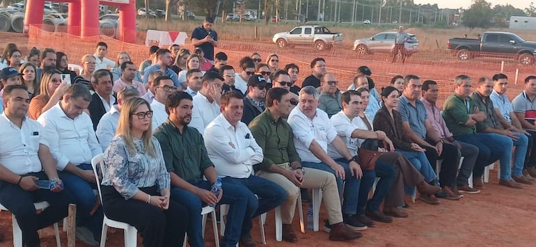 Marcelo Javier Soto Pavón y Luis Ramírez escuchan a un orador en un evento con público variado en sillas plásticas.