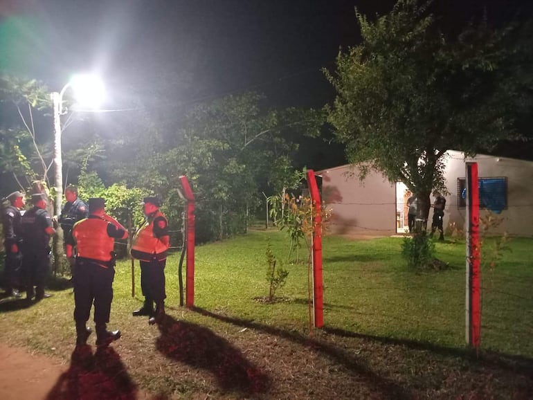 Agentes de seguridad discuten en un entorno exterior iluminado, vistiendo uniformes oscuros y chalecos naranjas.