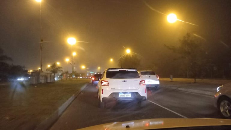 Escena de tráfico denso con vehículos de colores diversos en la Costanera de Asunción, en un ambiente brumoso por la niebla.