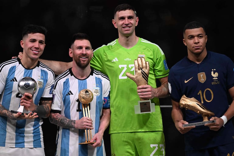 El mediocampista número 24 de Argentina, Enzo Fernández, el delantero número 10 de Argentina, Lionel Messi, el arquero número 23 de Argentina, Emiliano Martínez, y el delantero número 10 de Francia, Kylian Mbappé, posan en el podio tras recibir respectivamente los premios al Mejor Jugador Joven, el Balón de Oro, el Guante de Oro y la Bota de Oro, durante la ceremonia de premiación del Mundial de Qatar 2022, después del partido final de fútbol entre Argentina y Francia en el Estadio de Lusail.