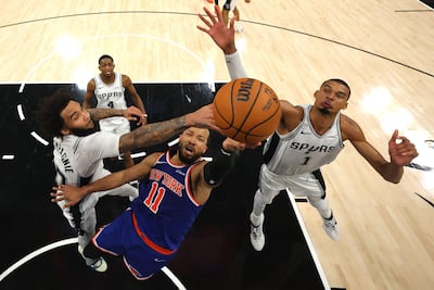 Jalen Brunson se dispone a encestar ante la oposición de Julian Champagnie y Victor Wembanyama, de San Antonio.