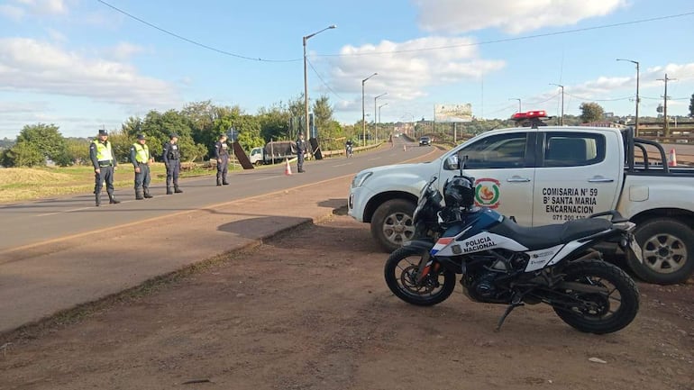 Cinco policías con chalecos reflectantes organizan el tráfico en control policial, con una moto y camioneta marcadas de la Policía Nacional.