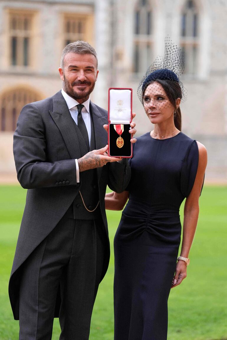 El exfutbolista inglés David Beckham posa junto a su esposa, Victoria Beckham, con su medalla tras ser nombrado Caballero en una ceremonia de investidura en el Castillo de Windsor. (Andrew Matthews / POOL / AFP)