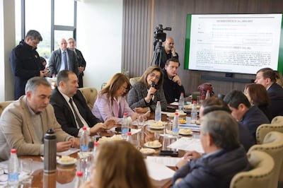 Blanca Ovelar habla con micrófono, rodeada de hombres y mujeres en una mesa con agua y comida, en un ambiente de reunión formal.
