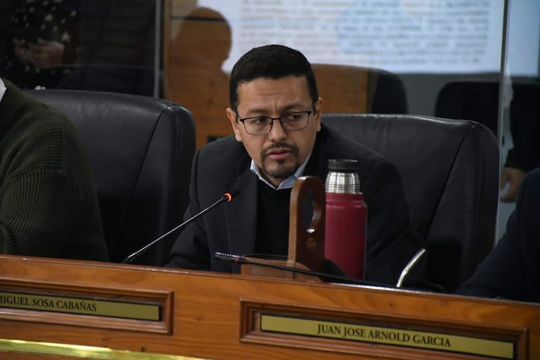 Miguel Sosa, de mediana estatura, con gafas y barba, habla concentrado en una mesa con botella térmica y micrófono.