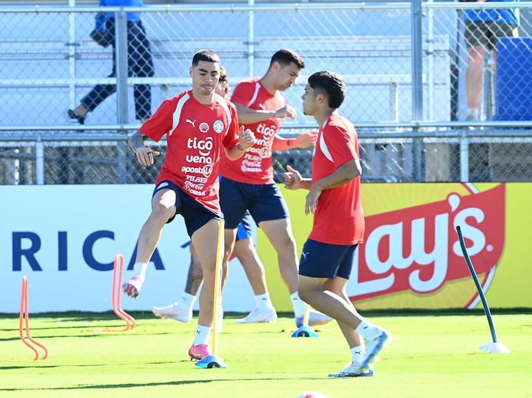 Miguel Almirón y Fabián Balbuena entrenan en césped natural, vistiendo camisetas rojas de Puma, con ambiente concentrado.