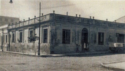 Edificio de estilo clásico de ladrillo con ventanas de rejas metálicas en una calle urbana sin actividad humana.
