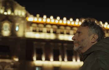 Fito Páez en entorno nocturno, mirando hacia arriba, con cabello rizado y barba, sin otros elementos visibles.