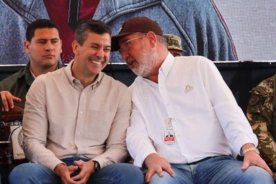 El presidente Santiago Peña (izq) sonriente conversa con el director de Itaipú, Justo Zacarías.