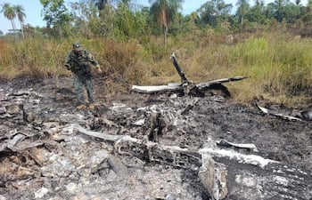 Un integrante de las Fuerzas Militares de Paraguay observa la una avioneta incinerada en el departamento de Concepción.