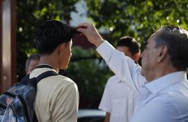 Un docente recibe a estudiantes del Instituto Nacional "General Manuel José Arce" este lunes y controla el largo de su pelo en San Salvador (El Salvador).