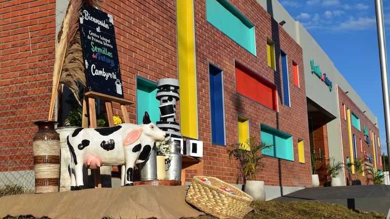 Fachada colorida del Centro Integral de Primera Infancia en un día soleado, con letrero de bienvenida y elementos decorativos rurales.