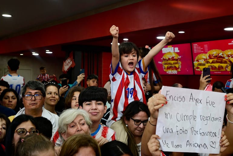 Ariana celebra su cumpleaños en La Joya Mostaza con un cartel, mientras Julio Enciso es el centro de atención entre la multitud contente.